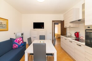 Ein kompakter Wohnbereich mit Essplatz, Küchenzeile und Fernseher.