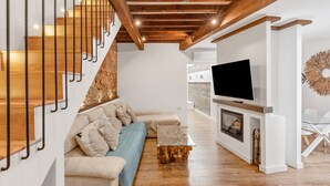 A modern living room with a wooden staircase, a sofa set, a flat-screen TV, and a fireplace. - Village house, 100m from the beach, with Wi-Fi and air conditioning (Estepona)
