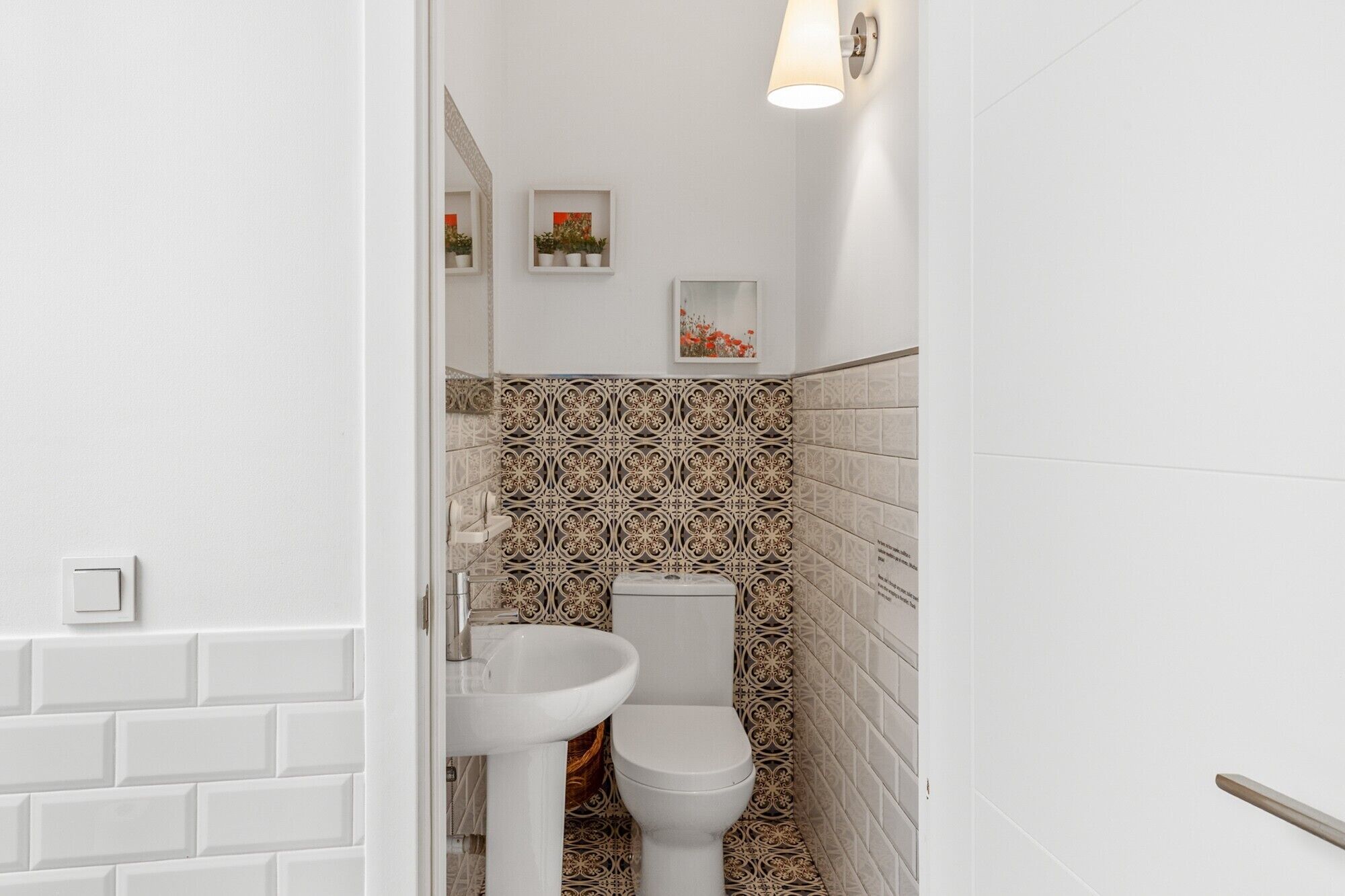 Un bagno con un water bianco, un lavandino bianco e piastrelle decorate sulle pareti.