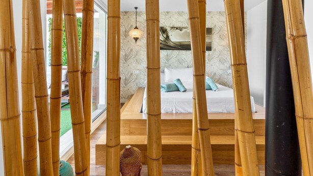 A room with a bed, a hanging light fixture, and bamboo columns. - Village house, 100m from the beach, with Wi-Fi and air conditioning (Estepona)