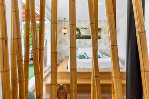 A room with a bed, a hanging light fixture, and bamboo columns. - Village house, 100m from the beach, with Wi-Fi and air conditioning (Estepona)
