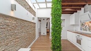 A modern kitchen with white cabinets, a wooden countertop, and a vertical garden. - Village house, 100m from the beach, with Wi-Fi and air conditioning (Estepona)