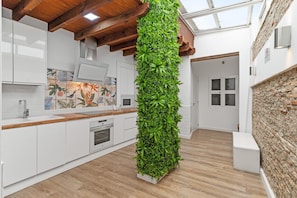 A modern kitchen with white cabinets, a wooden countertop, a built-in vertical garden, and a skylight. - Village house, 100m from the beach, with Wi-Fi and air conditioning (Estepona)