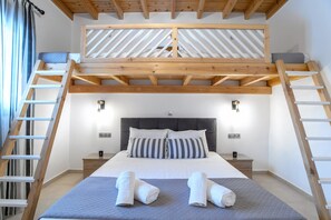 Un dormitorio con cama de altillo, escalera de madera, mesitas de noche y cabecera.