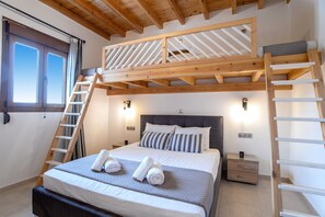 A bedroom with a bunk bed, a ladder, bedside tables, and a window with curtains.
