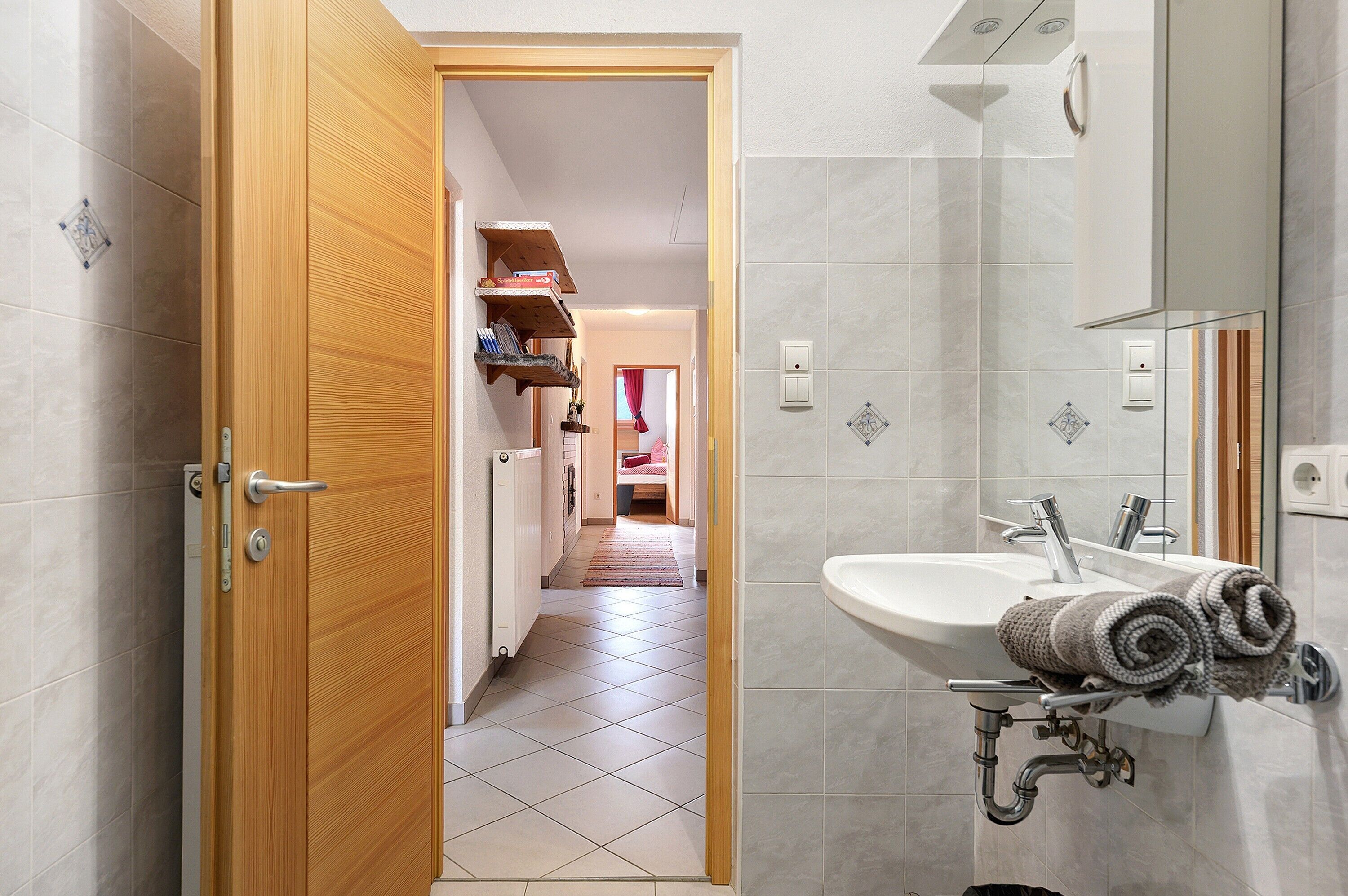 A bathroom with a sink, towel rack, and a wooden door leading to a hallway.