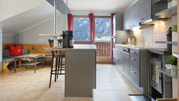 Una cocina moderna con una isla central, banco de madera y vistas a montañas a través de una ventana.