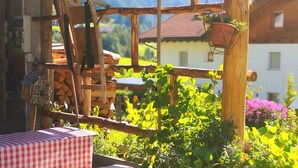 Una estructura de madera rústica con una mesa y sillas, rodeada de abundante follaje y vistas a la montaña.