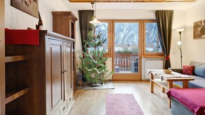 Una sala de estar acogedora con techo de madera, un árbol de Navidad, un sofá y una mesa de comedor.