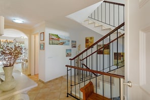 A staircase with a wooden handrail and black metal railings, leading to an upper floor.