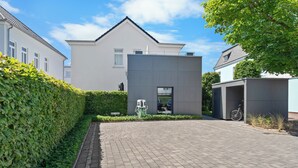 A modern house with a paved driveway, a garage, and a well-maintained hedge.