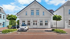 A white building with a symmetrical facade, a central entrance, and a paved driveway.