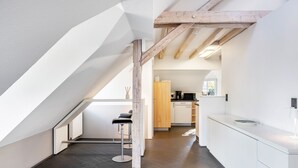 Eine moderne Küche mit weißen Schränken, Holzbalkendecke und dunklem Boden.