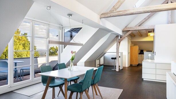 Ein modernes Interieur mit Essbereich, Küche und großen Fenstern.