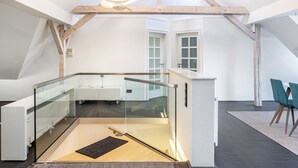 Ein modernes Loft mit Glasbalkon, Holzbalken und schlichtem Interieur.