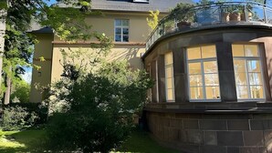 Ein zweistöckiges Haus mit Balkon, einem Fenster mit Aussicht und einem gepflegten Rasen.