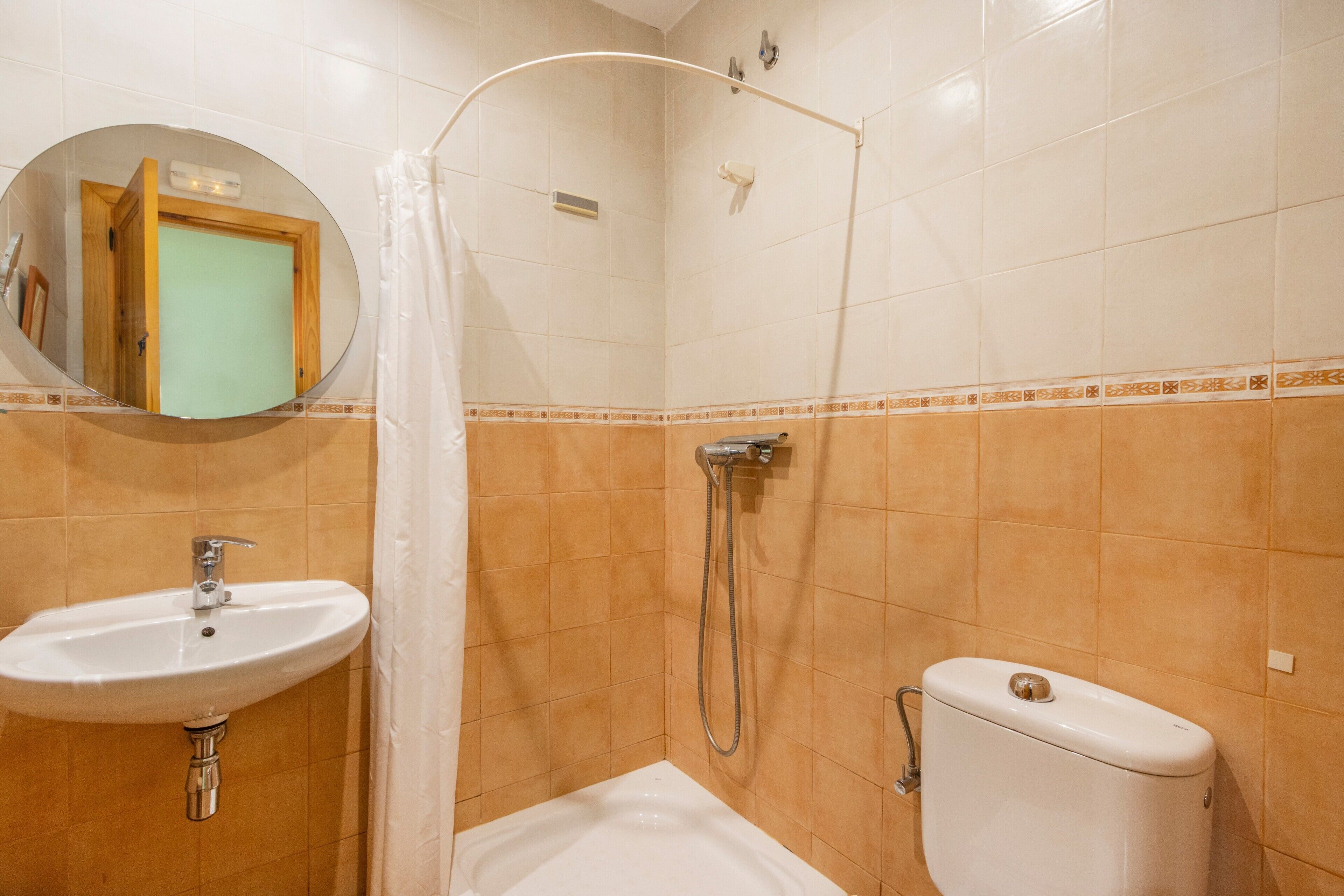 Une salle de bain équipée d’un lavabo, de toilettes, d’une douche et d’un miroir.