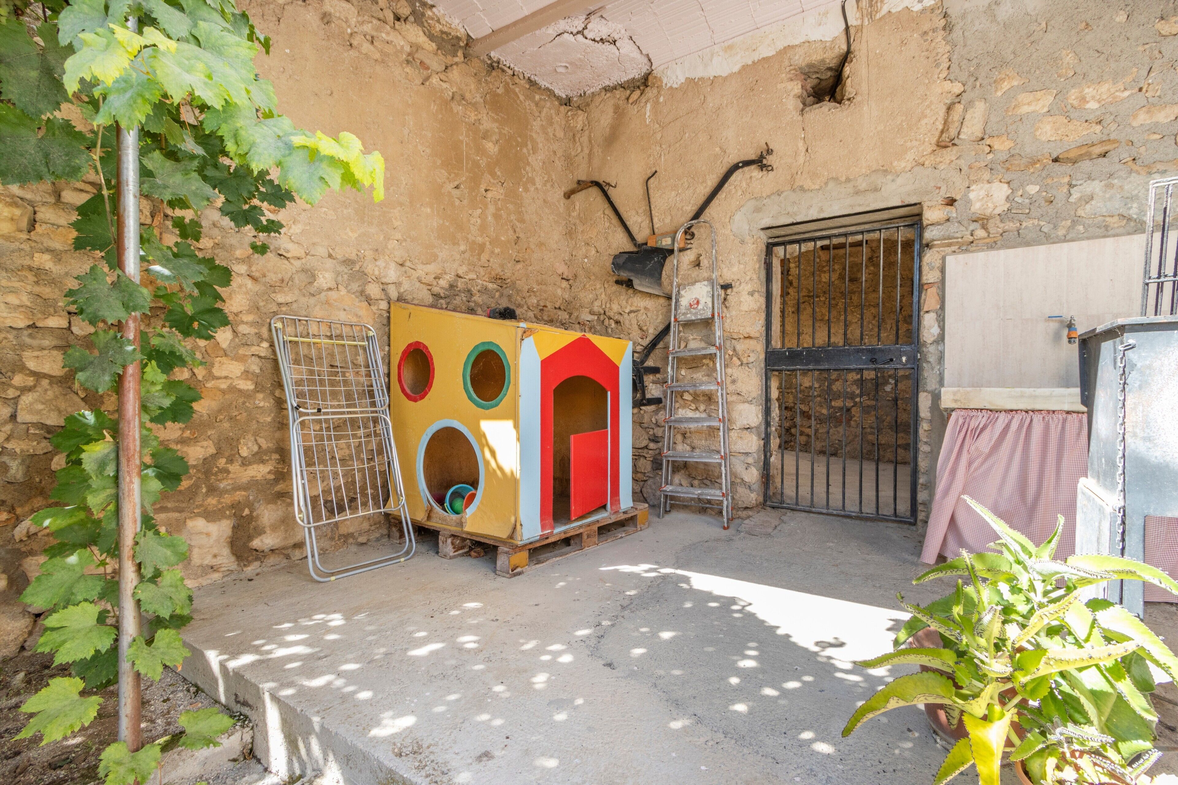 A rustic outdoor area with a playhouse, a ladder, and a gate.
