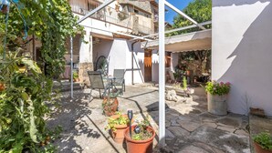 Un patio con plantas en macetas, una mesa y sillas.
