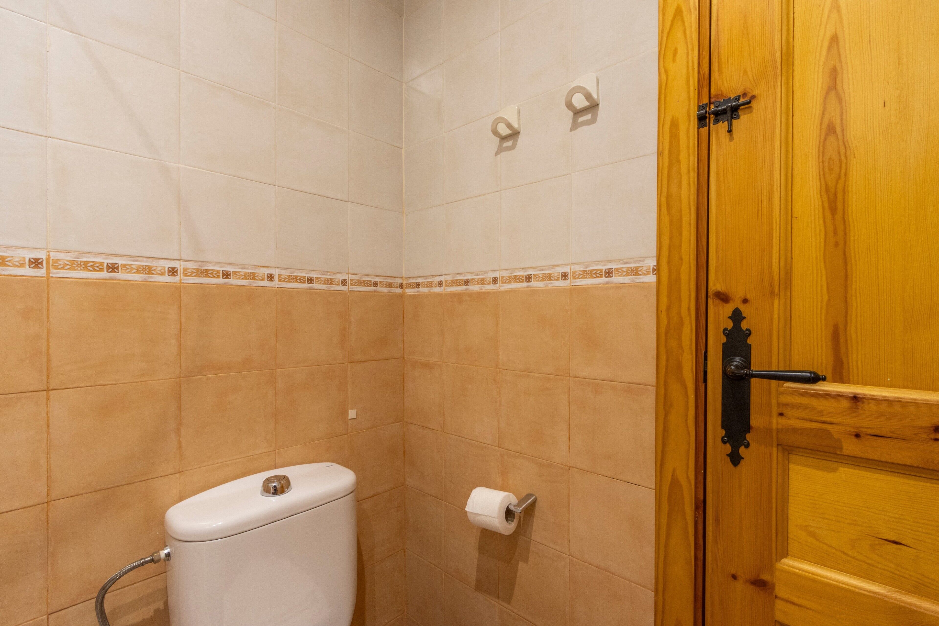 A small bathroom with a toilet, a towel rack, and a wooden door.