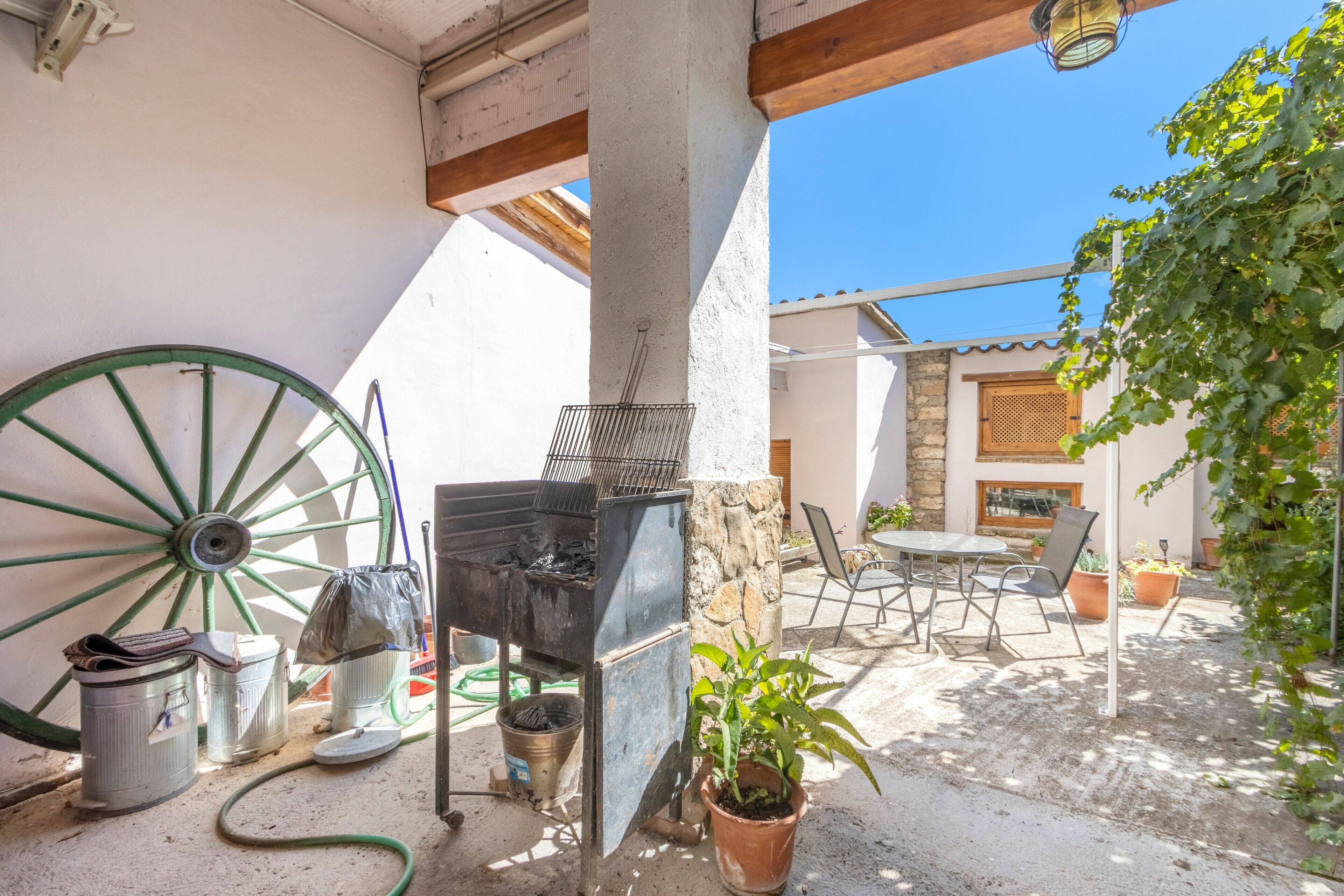 A patio with a grill, a wheelbarrow, and outdoor furniture.