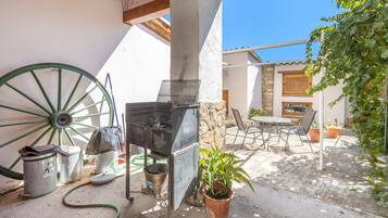 A patio with a grill, a wheelbarrow, and outdoor furniture.