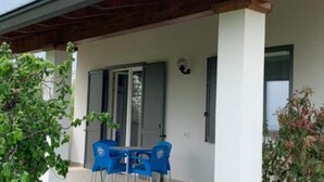 A covered outdoor area with a table and chairs, a door, and a window. - Apartment 'Lampone' with Mountain View, Private Terrace and Wi-Fi (Cantello)