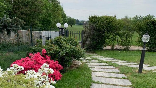 A stone pathway leading through a garden with various plants and a fence in the background. - Apartment 'Lampone' with Mountain View, Private Terrace and Wi-Fi (Cantello)