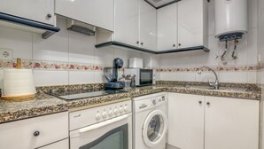 A kitchen with a washing machine, microwave, and a water heater. - Apartment 'On Daimús Beach' with Shared Pool, Wi-Fi and Air Conditioning (Daimús)