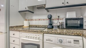 A kitchen with white cabinets, a microwave, a coffee maker, a Siemens dishwasher, and a washing machine. - Apartment 'On Daimús Beach' with Shared Pool, Wi-Fi and Air Conditioning (Daimús)