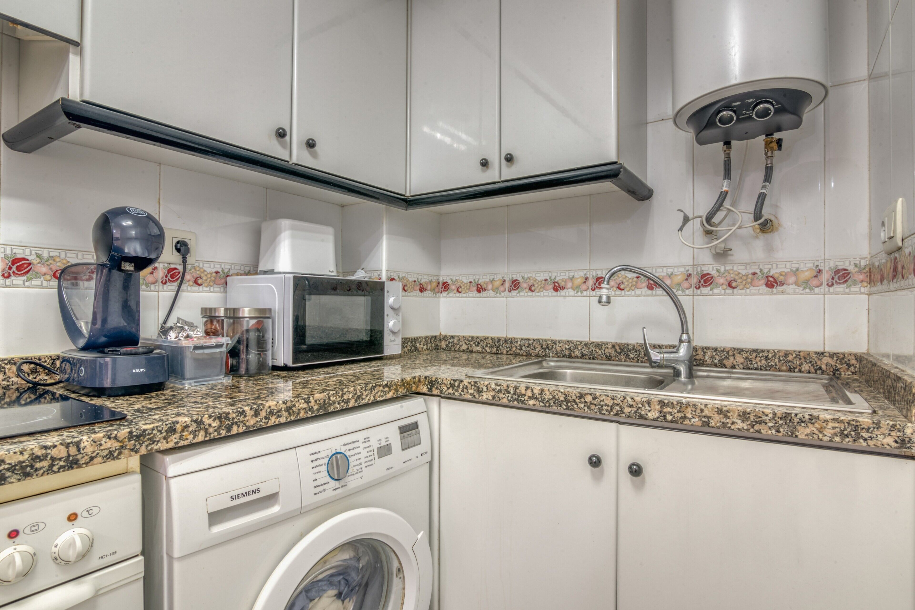 A kitchen with a microwave, toaster, sink, and washing machine.