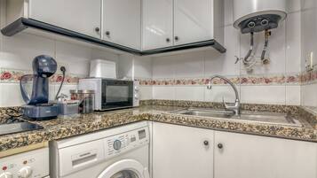 A kitchen with a microwave, toaster, sink, and washing machine.