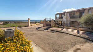 Un edificio con entrada protegida por una reja, un balcón y vistas al mar.