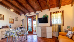 Una sala acogedora con mesa de comedor, sofá, televisor y zona de cocina.
