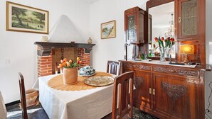 Een zithoek met een schouw van baksteen, een houten kast en een tafel gedekt met bloemen.
