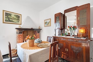 Un comedor con chimenea de ladrillo, mueble de madera y mesa adornada con flores.