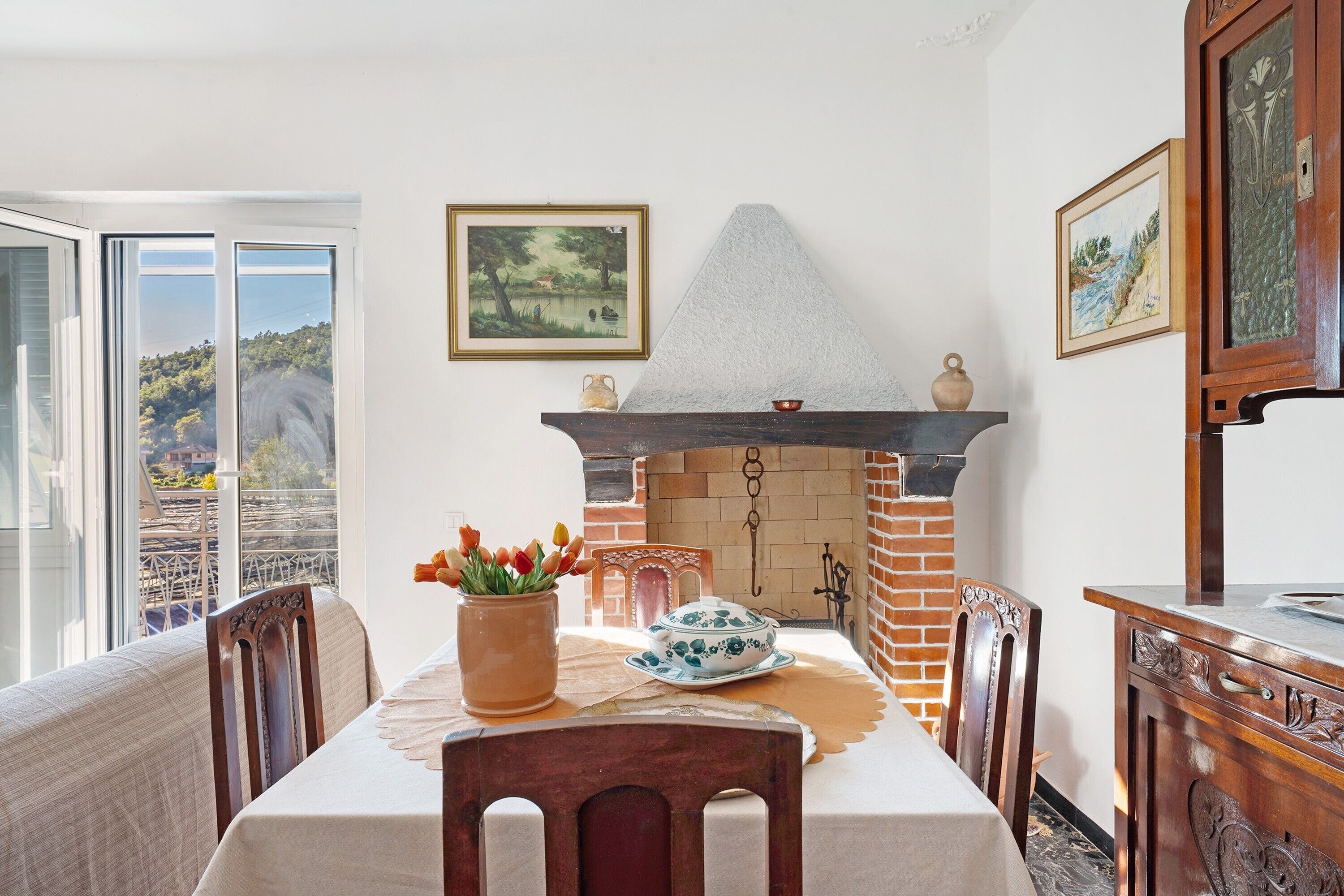 Un coin repas avec une table dressée pour deux personnes, une cheminée et une vue par la fenêtre.