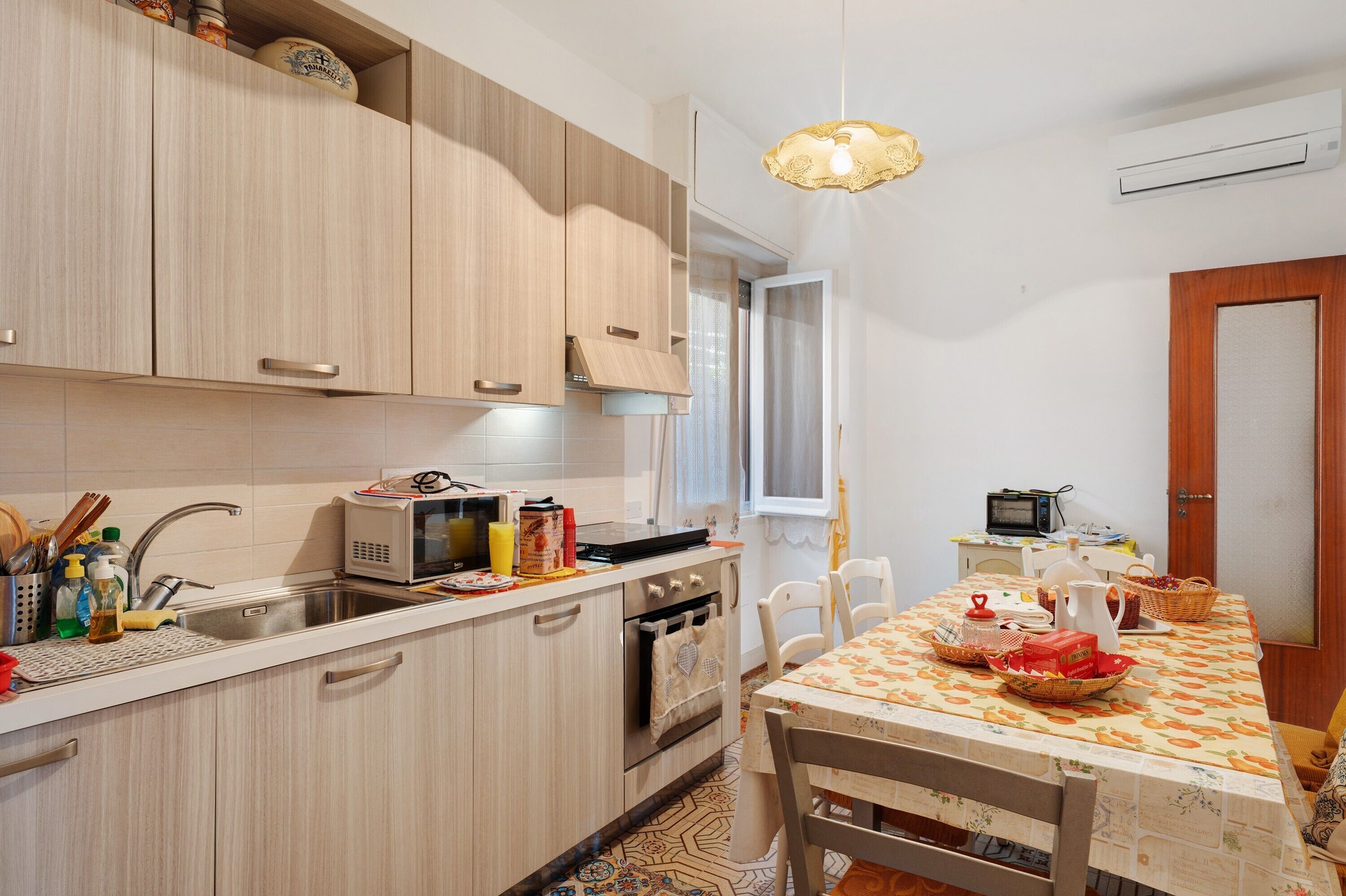 A kitchen with wooden cabinets, a microwave, a sink, and a dining table with chairs.
