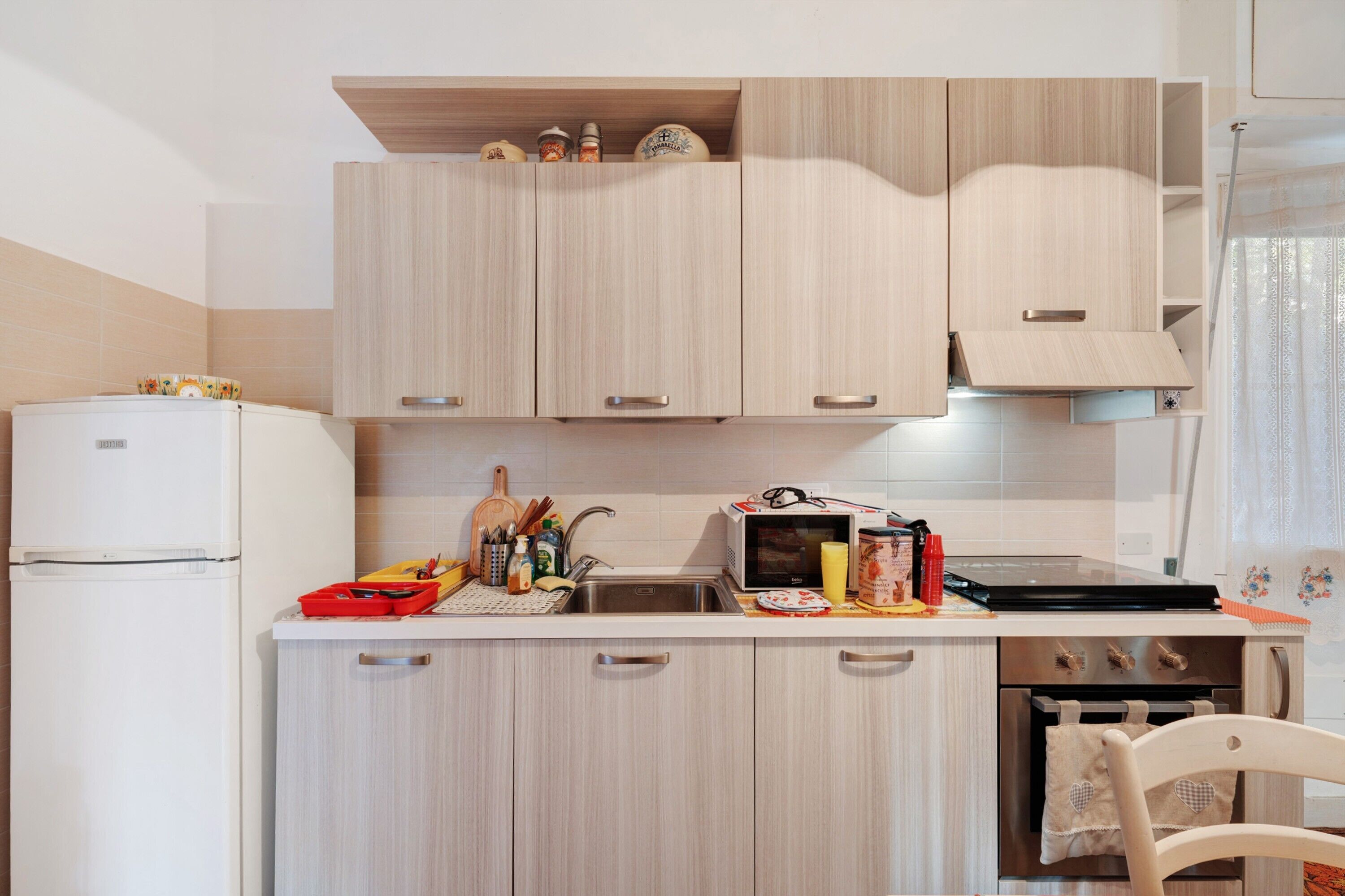 A kitchen with light wooden cabinets, a white refrigerator, a microwave, and a small oven.