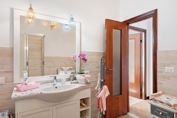 Un baño con lavamanos, espejo y puerta de madera.