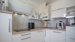 Una cocina moderna con armarios blancos, encimera de madera, cafetera y horno empotrado.