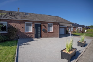 A brick building with a tiled roof, a covered entrance, and a paved driveway.