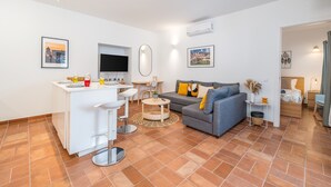 Un espacio habitable moderno con área de cocina, un sofá gris y una mesa de comedor.