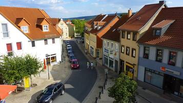 Straßenansicht mit traditioneller europäischer Architektur, eine Reihe geparkter Autos und Fußgänger.