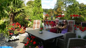 Une terrasse extérieure aménagée avec des meubles en osier, une table et des plantes en pot.