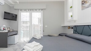 Een moderne hotelkamer met een bed, een bureau, een televisie en een balkon met uitzicht.