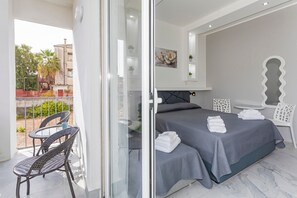 A hotel room with a balcony, a bed with neatly folded towels, and a dining area with chairs. - Room 'Dolce Relax - Comfort' with Balcony, Wi-Fi and Air Conditioning (Catania)