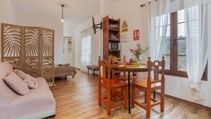Ein gemütliches Wohnzimmer mit einer Couch, einem Holzesstisch, Stühlen und einem dekorativen Schrank.