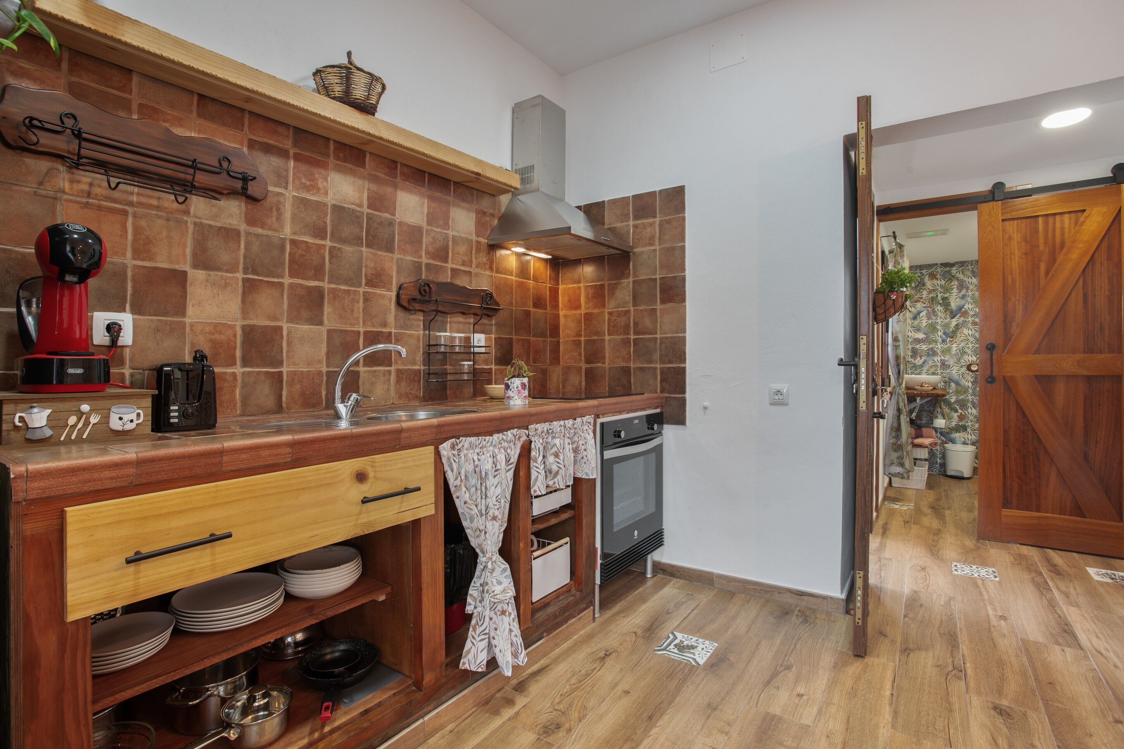 Una cocina compacta con horno integrado, cafetera y lavamanos.