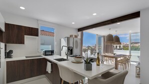 Una cocina moderna con una isla central, un comedor con vistas y un gran ventanal.